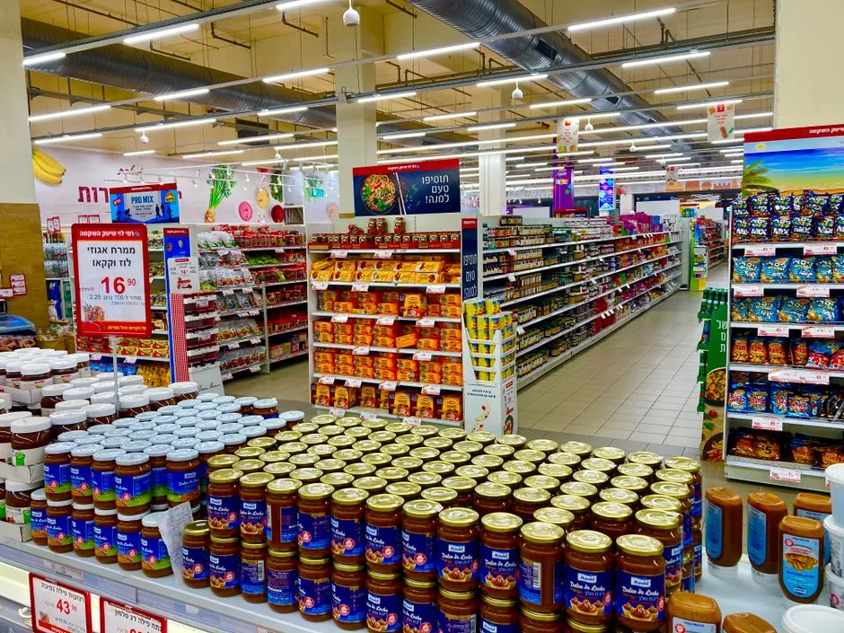 Fully stocked supermarket aisle with shelves of packaged groceries, illustrative of the store aisles our coupon data covers